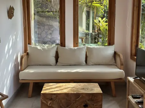 A modern wooden sofa with white cushions and a solid wood block coffee table.