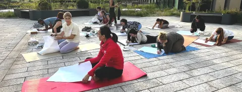 Participants in a rooftop wellness workshop using mats for a creative journaling and meditation session.