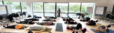 Group of people practicing savasana and meditation during an indoor wellness workshop.