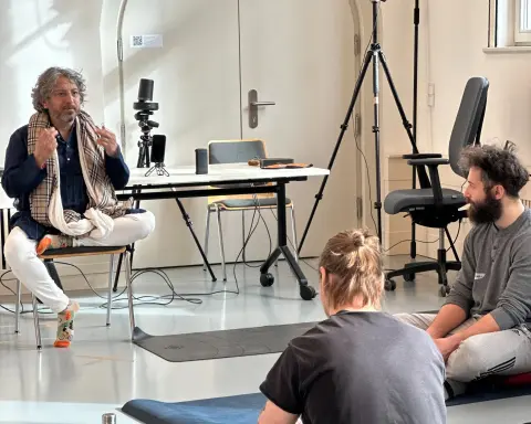 Indoor wellness workshop with participants seated on the floor listening to a speaker.