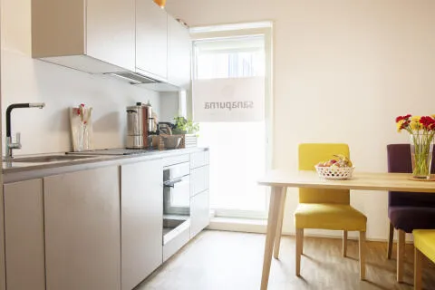 Shared kitchenette at the Sanapurna practice in Zurich, with Sanapurna branding on the window, wooden table and yellow chairs